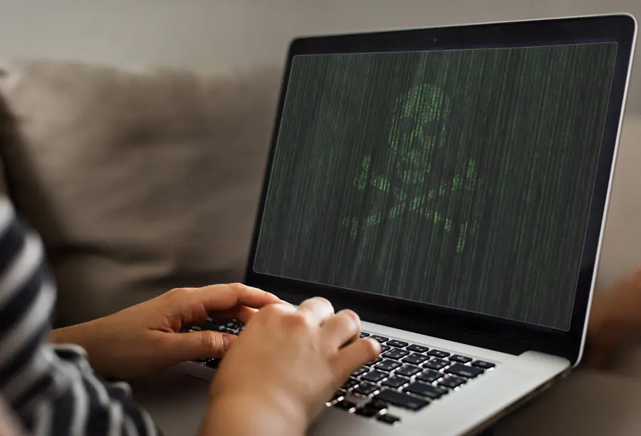How to Spot Malware - A Simple Guide | Chuck's Cyber Wall | How to Spot Malware - A Simple Guide | Chuck's Cyber Wall | How to spot malware Chuck's Cyber Wall image of a person typing on a laptop with a skull and crossbones displayed in code.