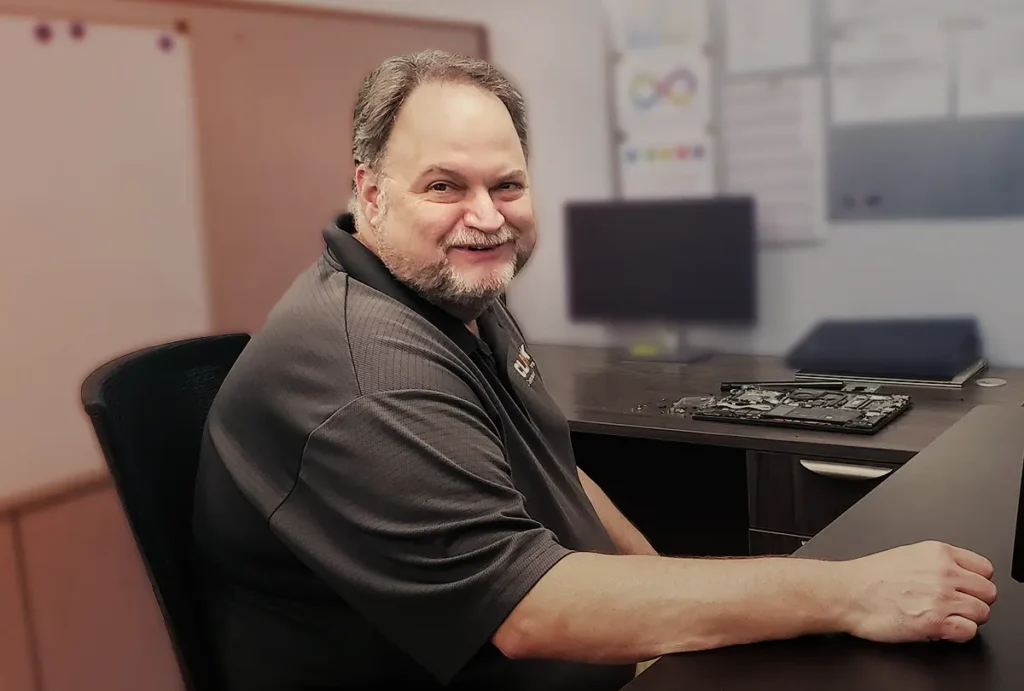 Construction IT Managed Services | Clark Computer Services | IT technician smiling at desk while providing Construction IT Support services for CLARK Computer Services