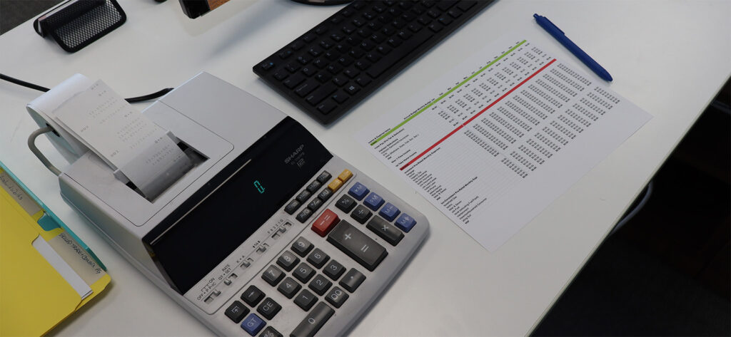 Finance IT Services image of calculator and spreadsheet on computer desk.